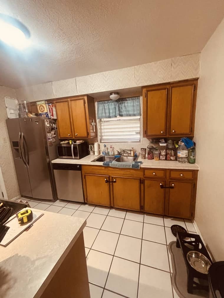 Dated kitchen with worn wood cabinets and old countertops before remodeling