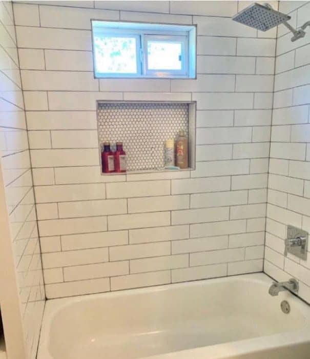 Same bath after Torres remodel with white subway tile, rain shower head, and built-in niche