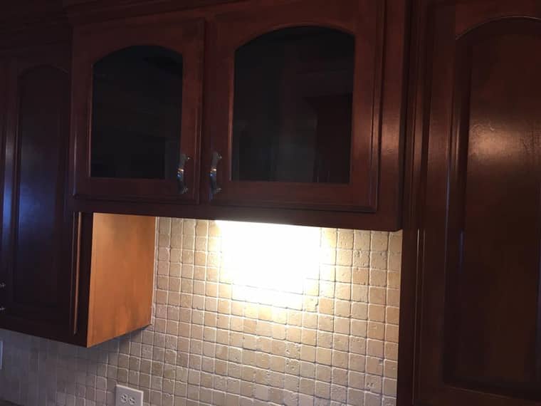 Glass-front cabinets with under-cabinet lighting and tile backsplash in Corpus Christi