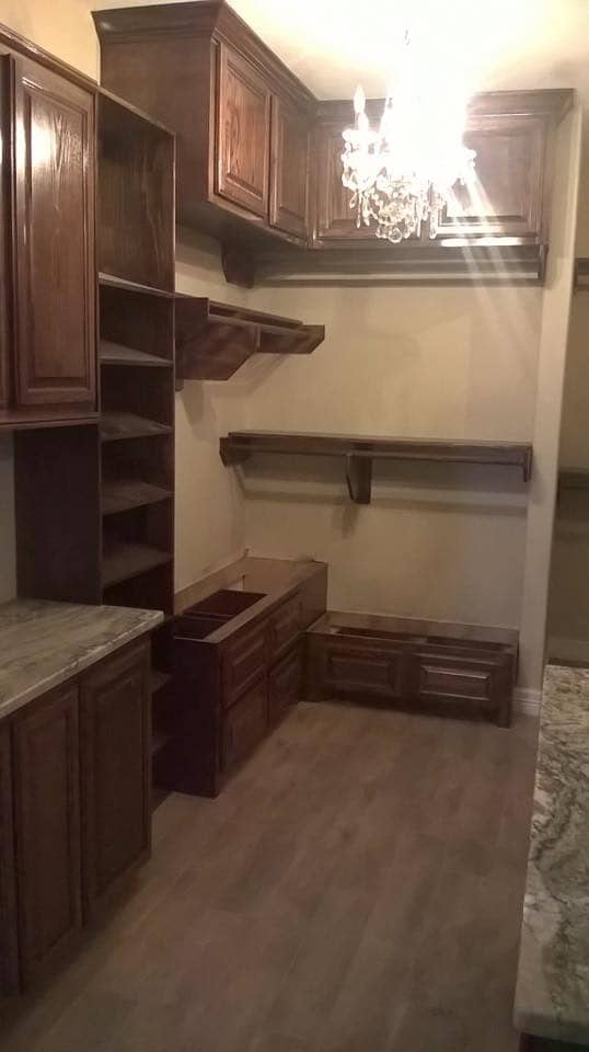 Custom dark walnut walk-in closet with shelving and chandelier in Corpus Christi