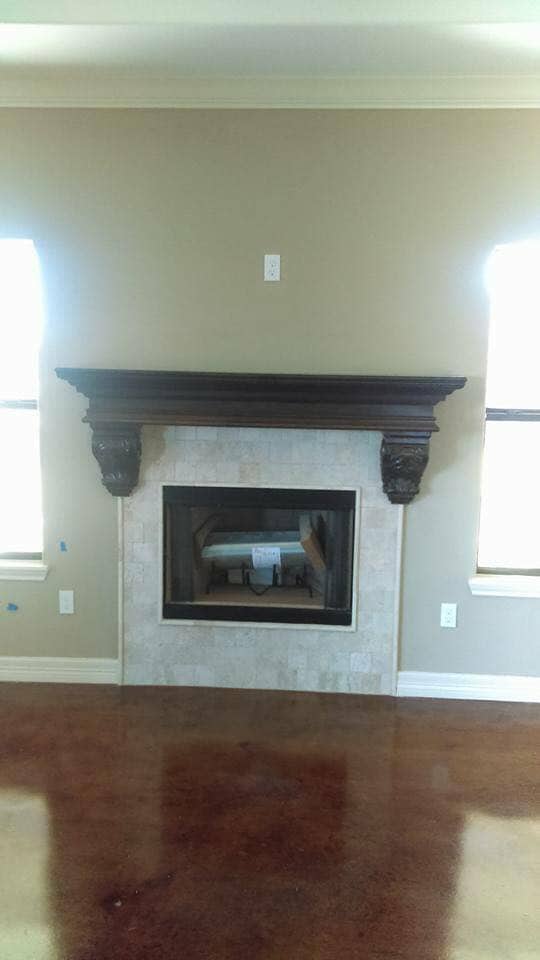 Custom fireplace mantel with travertine surround and stained concrete in Corpus Christi