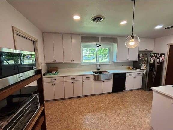 Same kitchen after Torres remodel with white cabinets, quartz countertops, and farmhouse sink