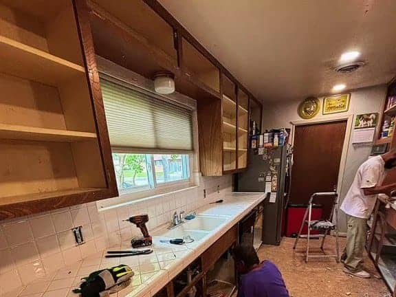 Dated kitchen with tile countertops and worn wood cabinets before remodeling in Corpus Christi