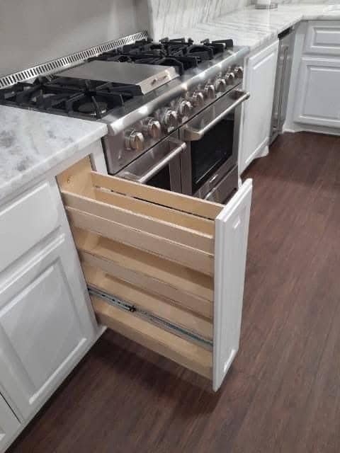 Custom pull-out spice drawer next to professional range in Corpus Christi kitchen