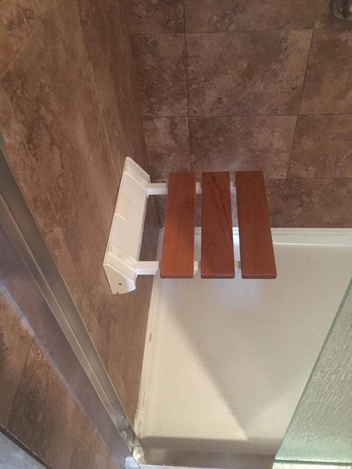 Folding teak shower bench with travertine tile in Corpus Christi